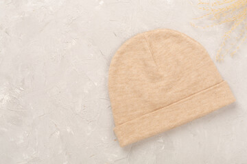 Stylish beanie hat on concrete background, top view