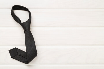 Black tie on wooden background, top view