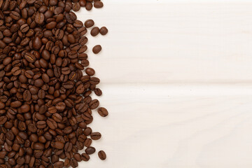 Roasted coffee beans with leaves on wooden background,top view