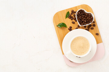 Cup of coffee with coffee beans and leaves on concrete background,top view