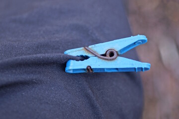 one old blue plastic clothespin pinches black fabric on clothes