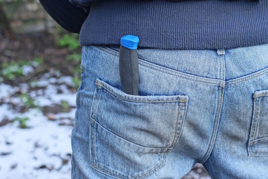 one knife with a black handle lies in the back pocket of blue jeans on a man on a spring street