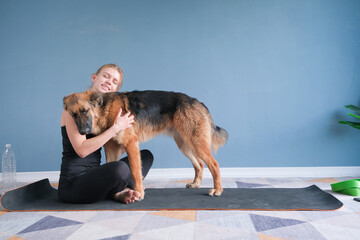 woman hugging her german shepherd dog while working out at home on yoga mat