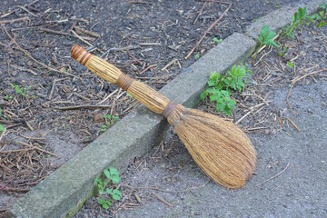 one old brown wooden broom lies on gray asphalt in the street