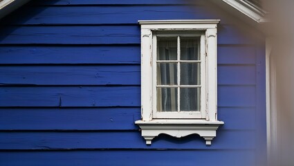 Fototapeta premium A striking blue house featuring a classic window framed in white.