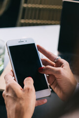 Cropped image of female millennial share media and publication in blog using smartphone with empty screen, woman's hand holding mobile phone making booking online and transaction via application