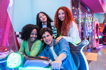 Group of young friends enjoying a lively time playing arcade racing games in a vibrant bowling...