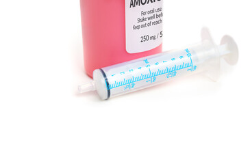 Liquid amoxicillin bottle with syringe. Fake generic label. Amoxicillin oral suspension. Penicillin antibiotic used by pediatricians and dentists for kids, children or adults. Selective focus.