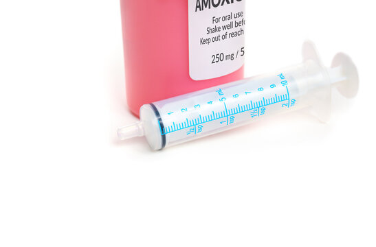 Liquid amoxicillin bottle with syringe. Fake generic label. Amoxicillin oral suspension. Penicillin antibiotic used by pediatricians and dentists for kids, children or adults. Selective focus.