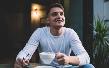 Cheerful smiling man drinking coffee in cafe