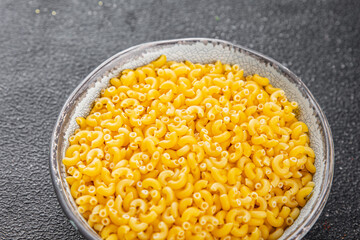 Pasta raw coquillette macaroni appetizer dish organic product fresh tasty gourmet food background on the table rustic food top view copy space