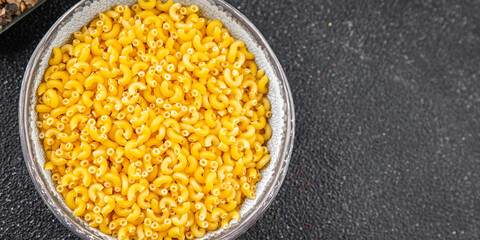 Pasta raw coquillette macaroni appetizer dish organic product fresh tasty gourmet food background on the table rustic food top view copy space