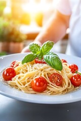 A waiter presents a plate of spaghetti with cherry tomatoes and basil