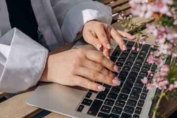 close up women's hands with elegant manicures are typing on a laptop keyboard