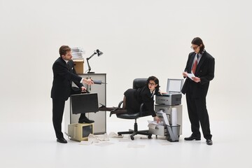 Female employee in surreal pose reaching inside drawer while male colleague offers notebook during...