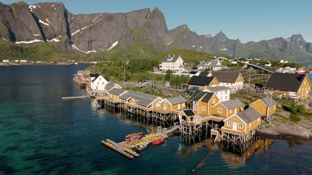 A stunning coastal village in Norway showcases vibrant orange cabins sitting atop stilts above crystal-clear waters. Sakrisoy, Moskenes, Lofoten islands. Norway.