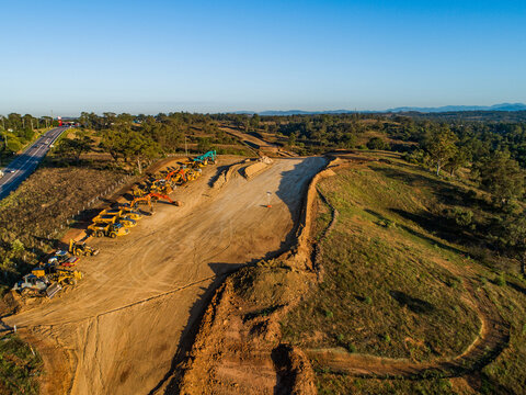 Machinery on worksite lined up in morning light ready to continue construction on bypass road