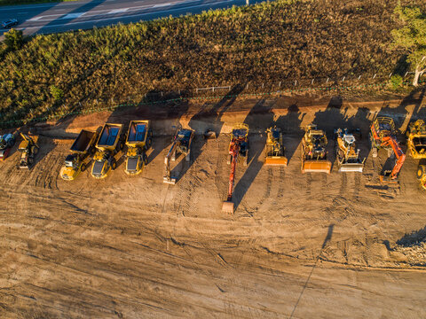 Machinery on worksite lined up in morning light ready to continue construction on bypass road
