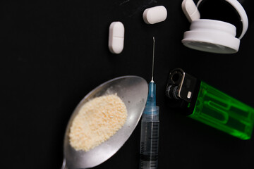 Narcotic drugs with syringe and spoon, isolated dark background