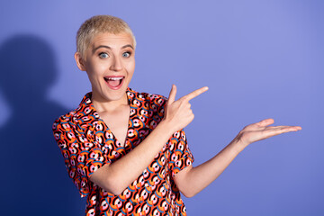 Joyful young woman with short hair gesturing enthusiastically, wearing a colorful patterned shirt,...