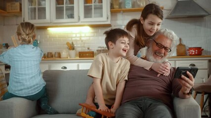 A happy grandfather and his grandchildren are having fun using a mobile phone, looking at the device screen, using funny apps, watching funny videos, playing video games - Powered by Adobe