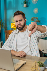 Dislike. Upset Caucasian business man at home office room showing thumbs down sign gesture,...