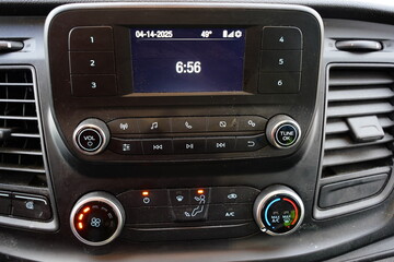 Center com controls of radio, LCD screen, and climate control inside a vehicle.