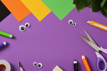Items for paper crafts in Halloween colors. Pencil, glue, eraser, knife, scissors and colored pieces of paper.