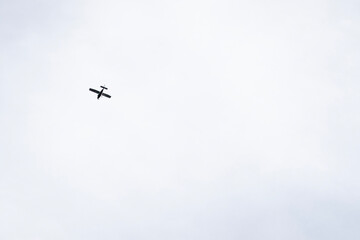 Small white airplane flying in clear blue sky, captured mid-air from below. Minimalistic composition with vibrant sky as background, symbolizing freedom and travel.

