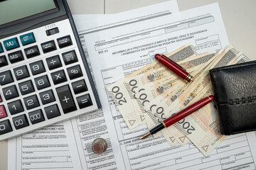 Filling polish tax forms PIT-11 with pen money zloty pln pen on table, Tax sheets