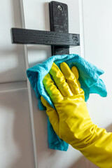 close up female hand cleaning door handle with gloves and napkin during a coronavirus pandemic