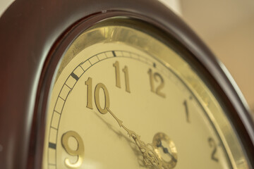 Close-up of a classic wall clock with gold accents showing the time at 10:00, emphasizing vintage...