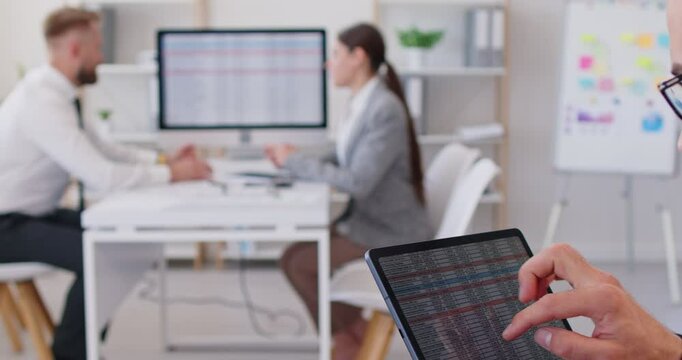 Focused busy analyst checking annual financial report analyzing business data on tablet screen in office using new professional software for digital graphic statistic analysis, economic market graphs