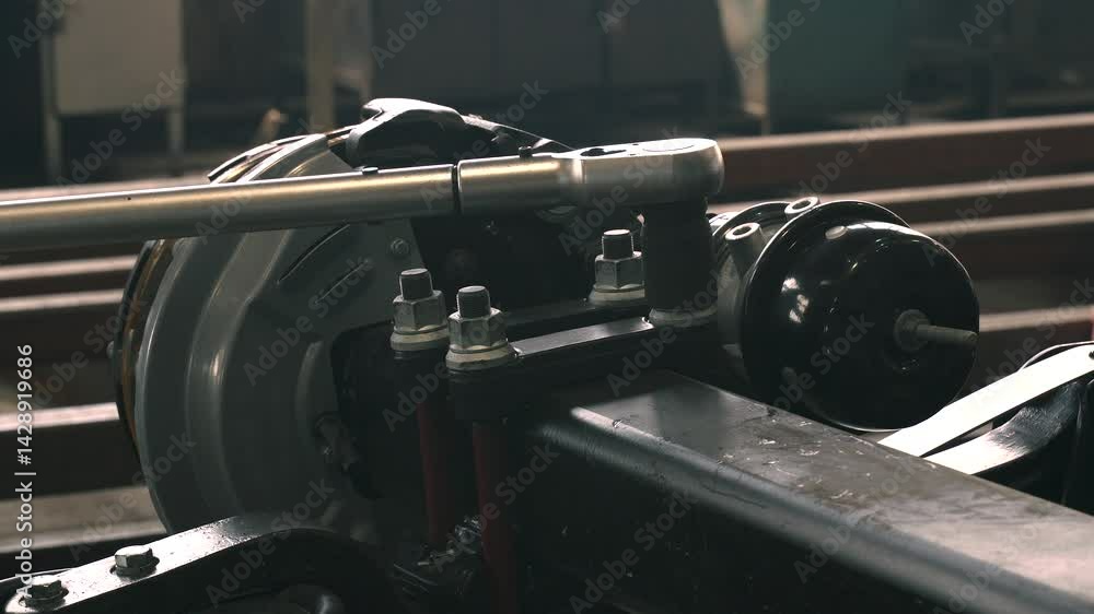 Poster In a workshop setting, a technician meticulously tightens a nut with a torque wrench, ensuring optimal force for securing essential components of machinery in operation.