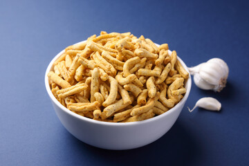 Indian snacks called Garlic Sev serve in bowl isolated on blue baclground