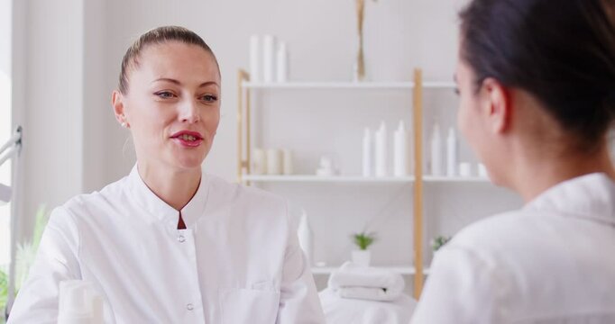 Professional doctor, cosmetologist talking consulting young female patient on face care skin study, beauty treatment, improving, visiting for facial cleansing, moisturizing in spa salon, beauty clinic