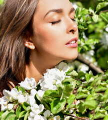 Fototapeta premium Happy young woman in a flowering spring garden. Spring time. Flowers blossoms.
