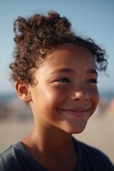 child smiles joyfully at beach with ocean gently blurred in background
