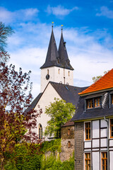 Church “Oberste Stadtkirche“ in Iserlohn (Sauerland) with twin towers, “Varnhagensche Bibliothek“ (Library) and truss house in the old german town. Idyllic view of historic buildings on a spring day.