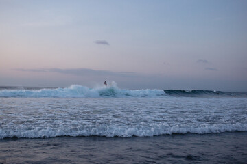 Surfer catches waves in the ocean at sunset in the evening. Surfer rides a shortboard