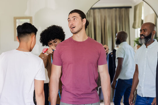Wedding suits, measuring customers and staff inside fitting room, with blue tape measure, mirror