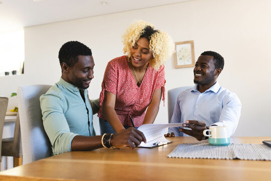 Couple and african american real estate advisor discussing new home at kitchen table, with tablet