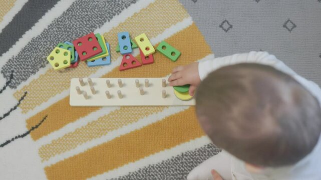 Baby playing with colorful wooden geometric shape sorter toy