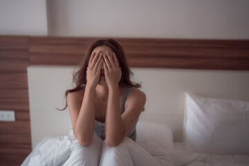 Sad woman sitting on bed covering her face with hands showing negative emotion, suffering from psychological problem, loneliness, grief, sadness, emotional stress or domestic violence