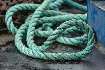 Coiled green rope on wet surface near blue metal edge