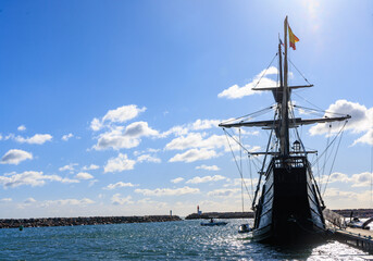 Vieux bateau &agrave; quai de type caraque dans un port ferm&eacute; par deux phares