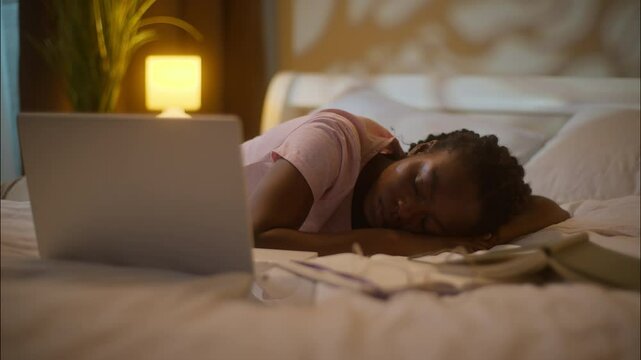 Tired exhausted African American ethnic woman female lady girl student lying bed sleeping opened laptop computer working insomnia studying homework deadline fatigue sleep bedtime at home late night
