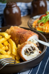 Fried chicken breast stuffed with mushrooms and cheese wrapped in ham served with fries and salad.