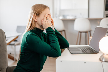 
Young woman sitting at desk, rubbing tired eyes from screen fatigue and stress. Concept of digital...