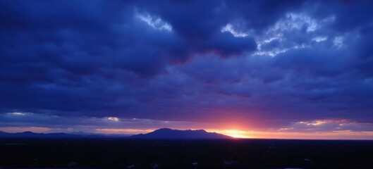 Dramatic sunset over mountains with vibrant colors and rich cloud formations.